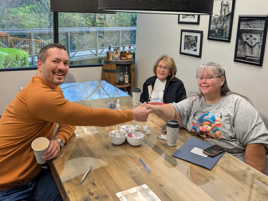 Dan shaking hands with two sellers across the closing table